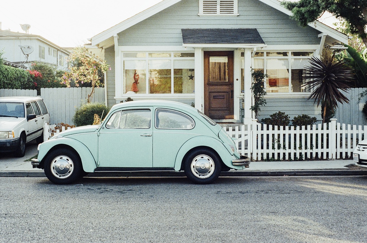 A blue vintage car parked in front of a house